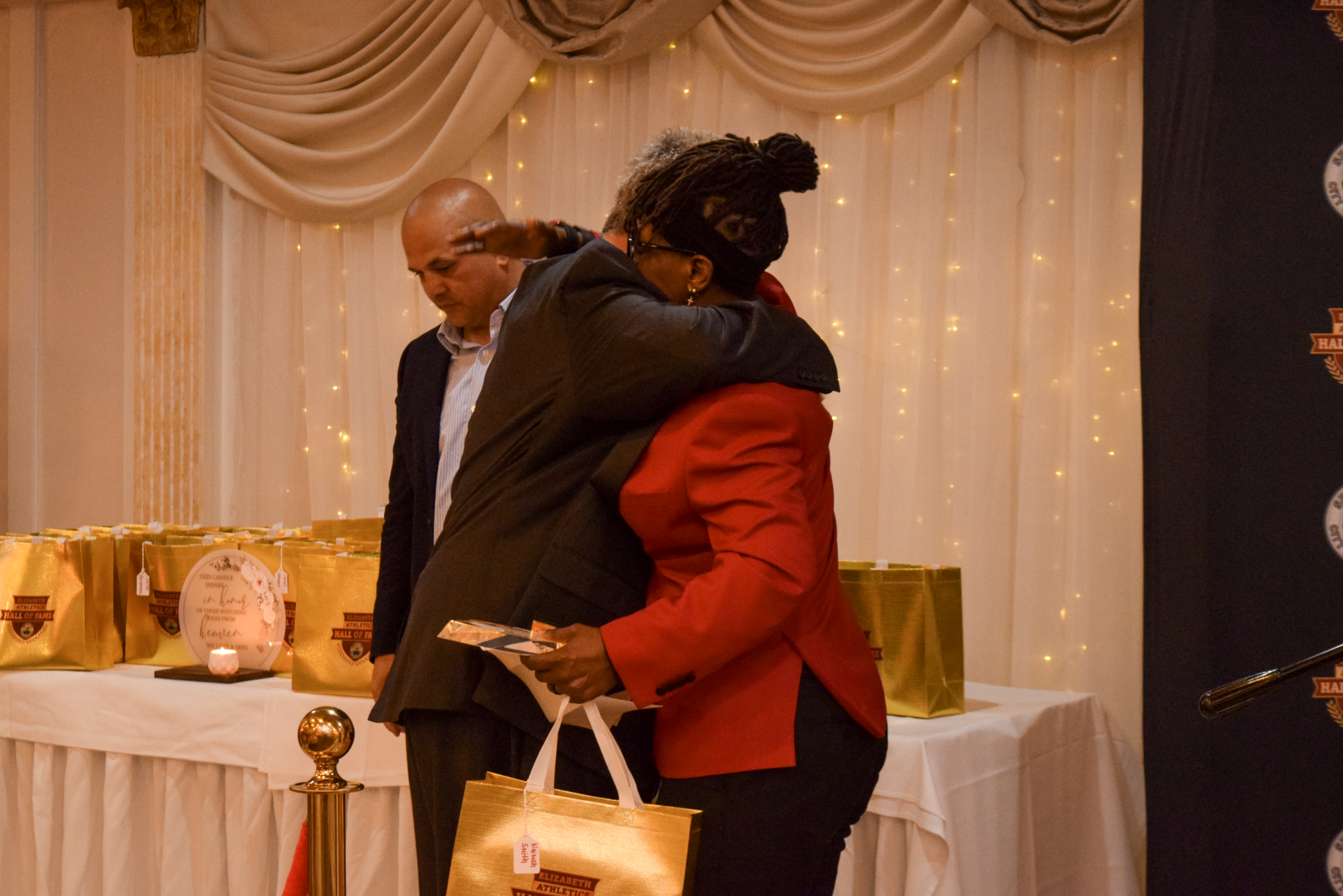 Board Member Oscar Cortizo embraces inductee Naimah Smith after reading her biography and presenting her awards.